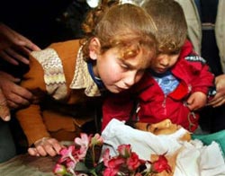 The sister and brother of Palestinian boy Ahmed Abu Elwan, 13, look at his face during his funeral in Rafah, southern Gaza Strip February 26, 2003. Ahmed Abu Elwan was killed when passing a car being shelled by the Israeli Defense Forces